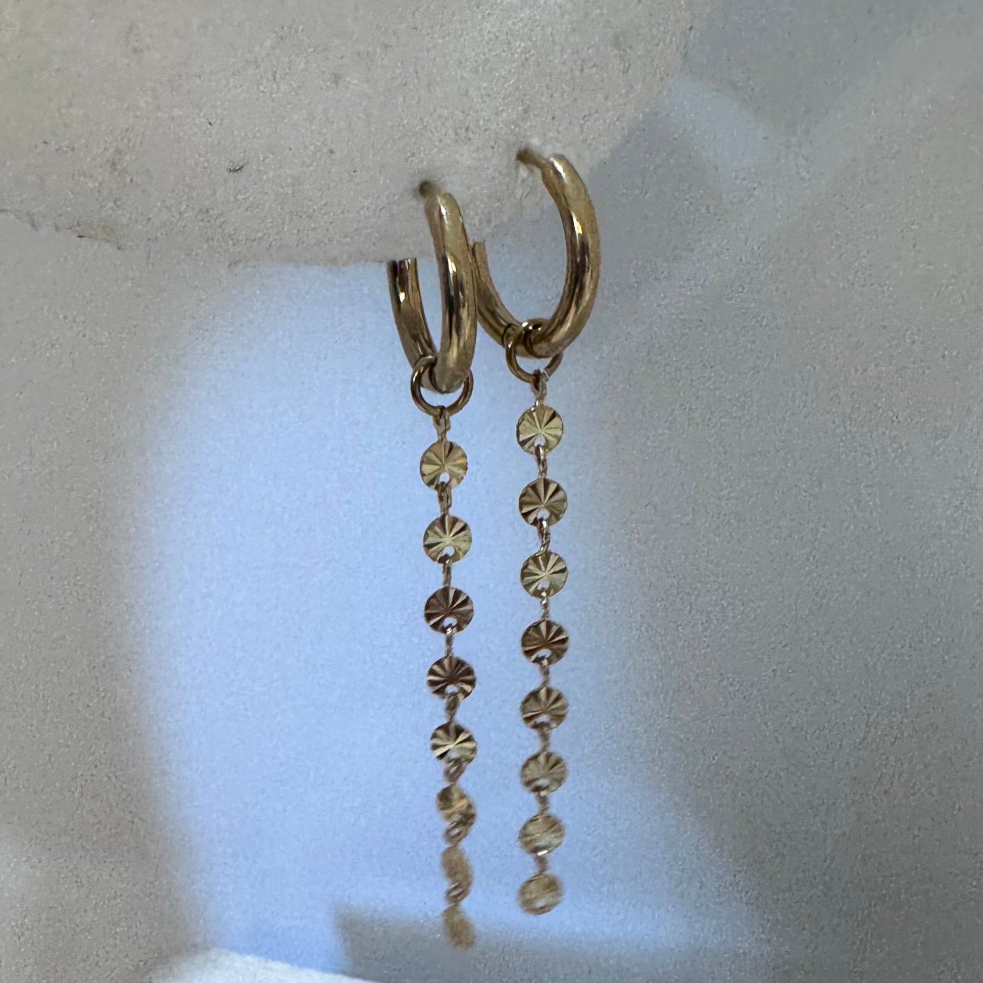 Gold necklace on a white stand with a speckled gray surface