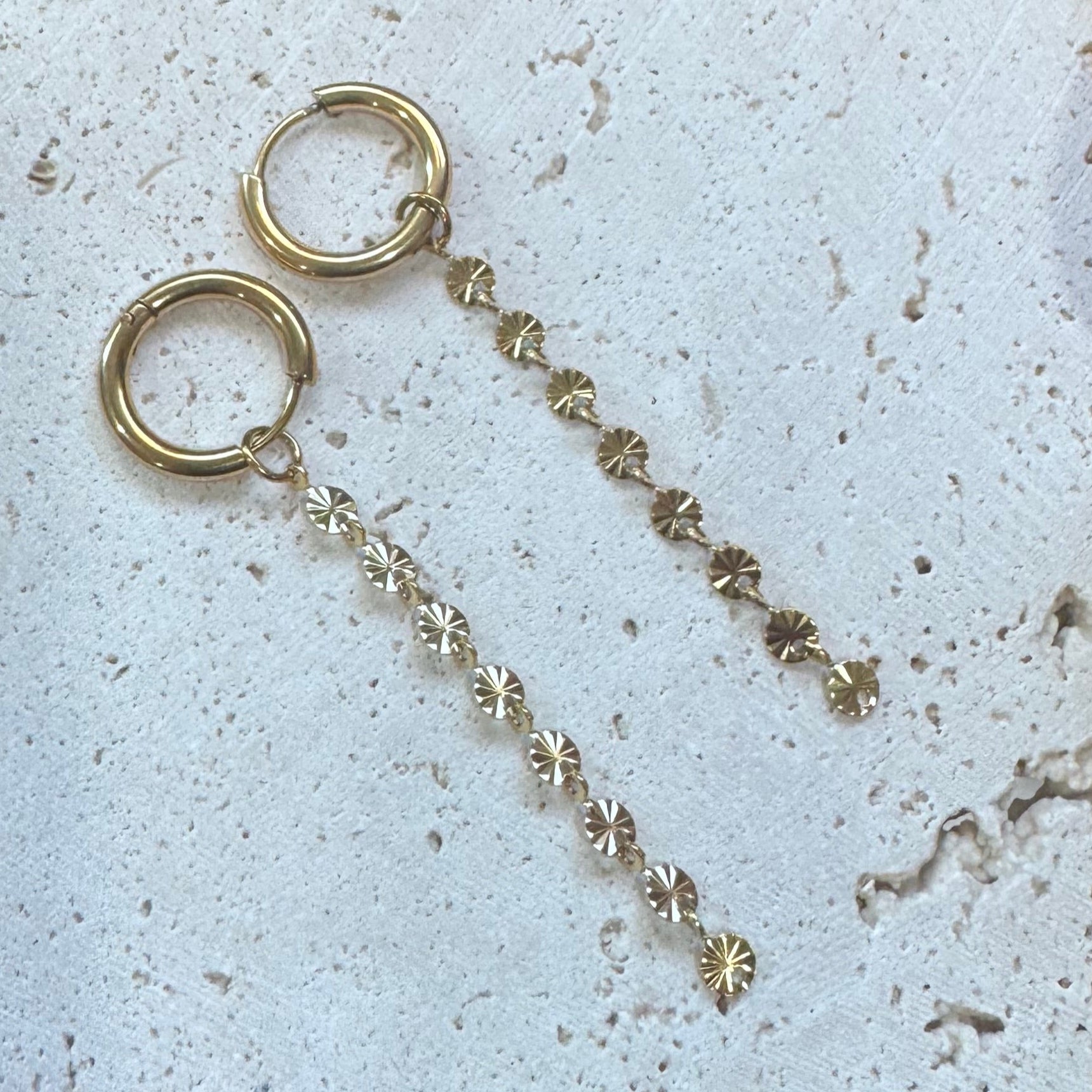 Gold necklace with interlocking rings on a textured white surface